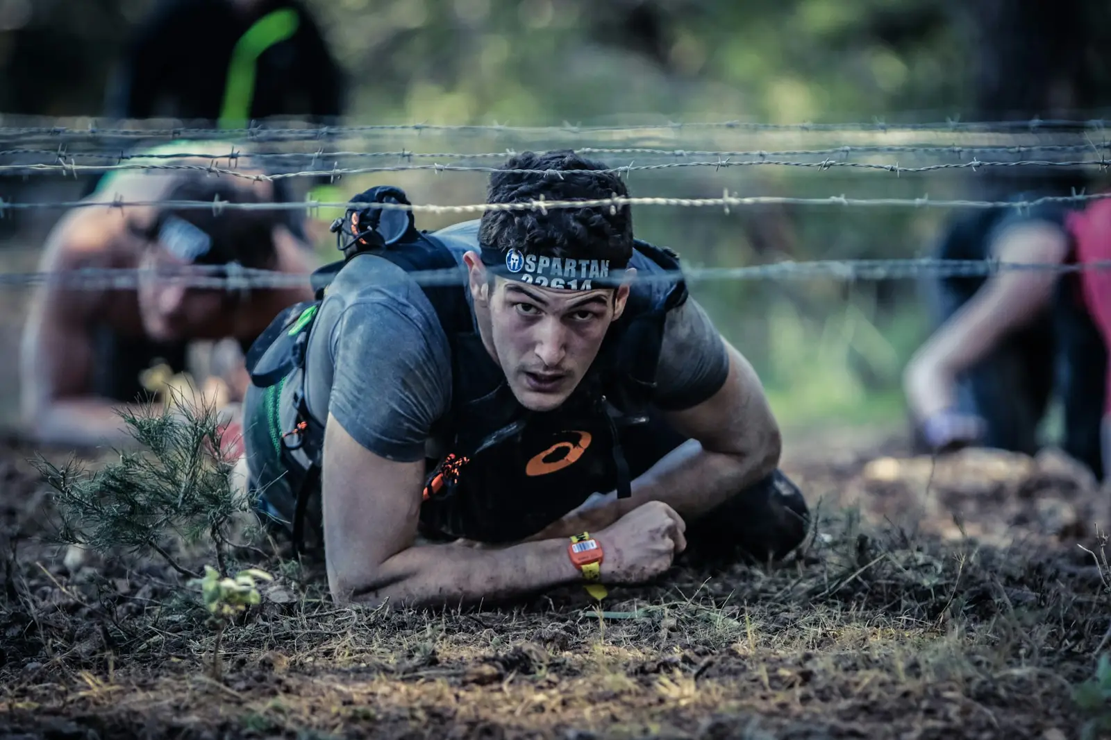Coureur rampant sous des barbelés pendant une course d’obstacles