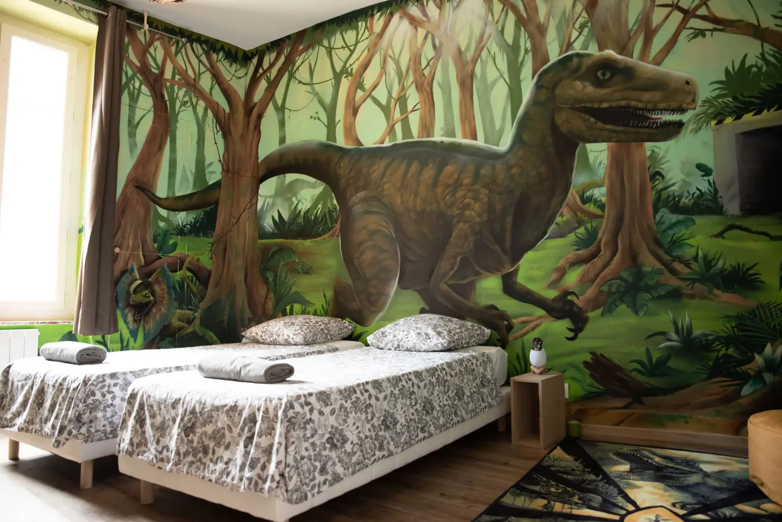 Chambre dinosaures : deux lits simples devant une fresque géante de jungle