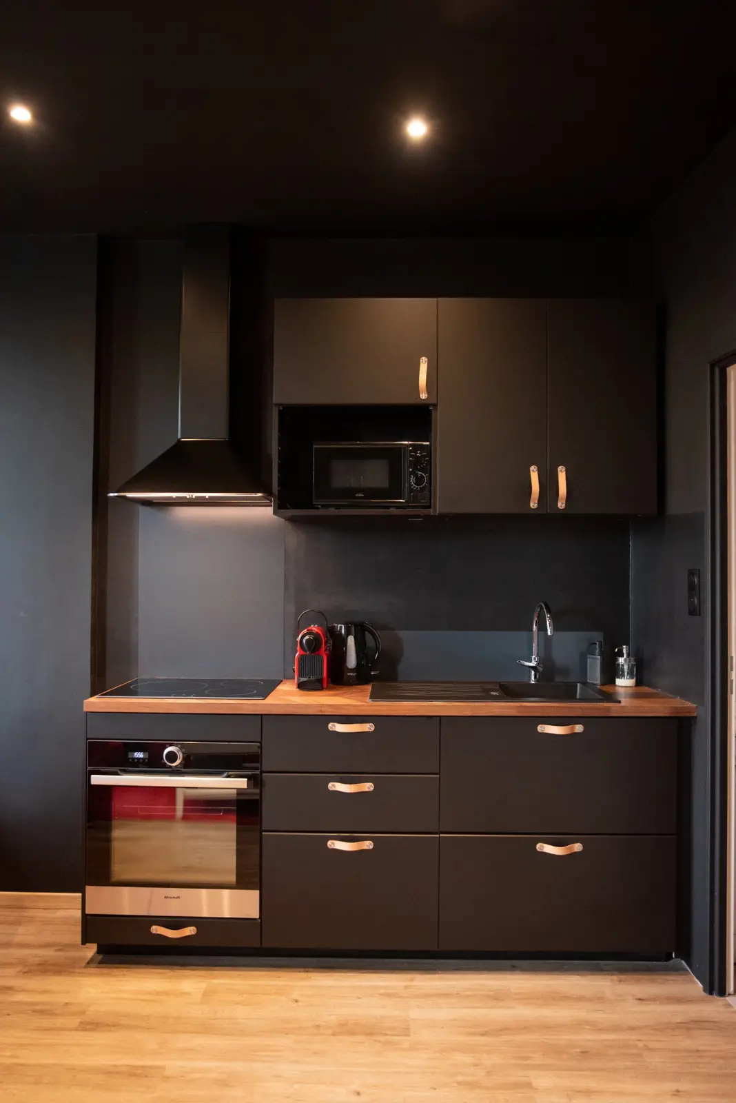 Cuisine noire équipée : four, plaque à induction, micro-ondes et machine à café