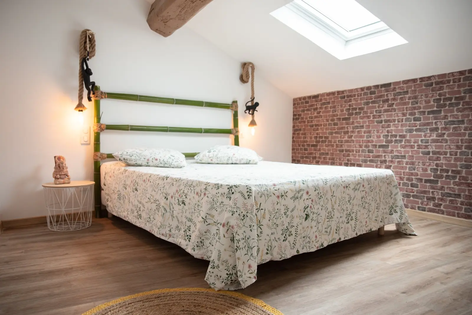 Chambre bambou : lit double, tête de lit en bambou, appliques en corde et fenêtre de toit