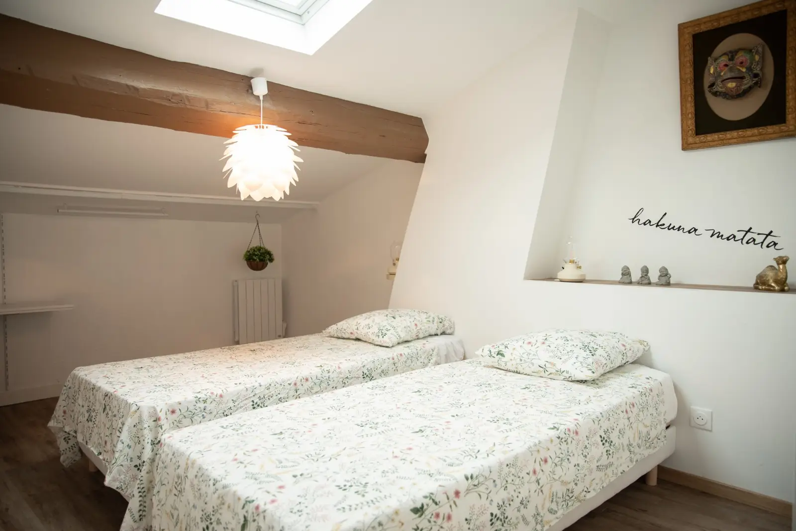 Chambre zen : deux lits simples sous une poutre et suspension blanche
